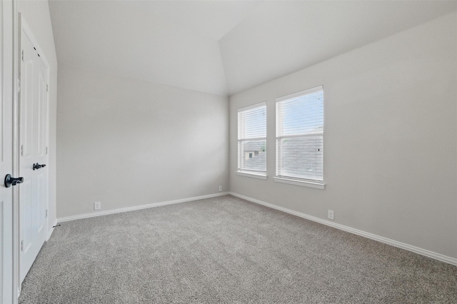 carpeted spare room with baseboards and vaulted ceiling