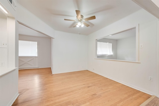 empty room with plenty of natural light, baseboards, ceiling fan, and light wood finished floors