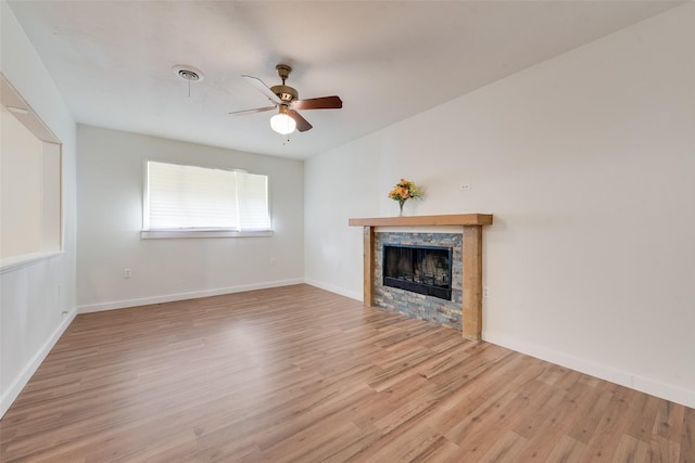 unfurnished living room featuring ceiling fan, visible vents, a fireplace, wood finished floors, and baseboards