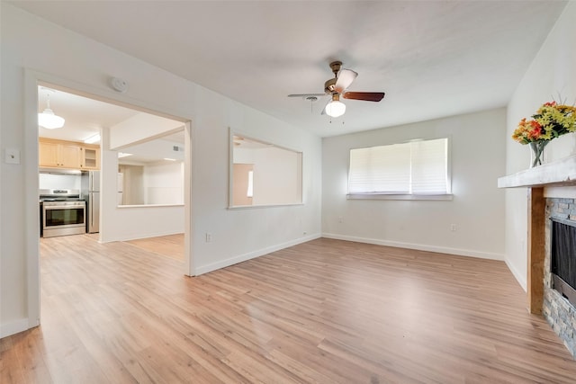 unfurnished living room with a ceiling fan, light wood-style flooring, and a fireplace