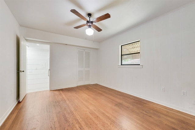 empty room featuring a ceiling fan, baseboards, and light wood finished floors