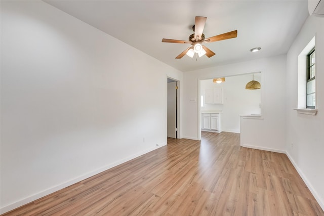 unfurnished room featuring baseboards, a wall unit AC, a ceiling fan, and light wood-type flooring