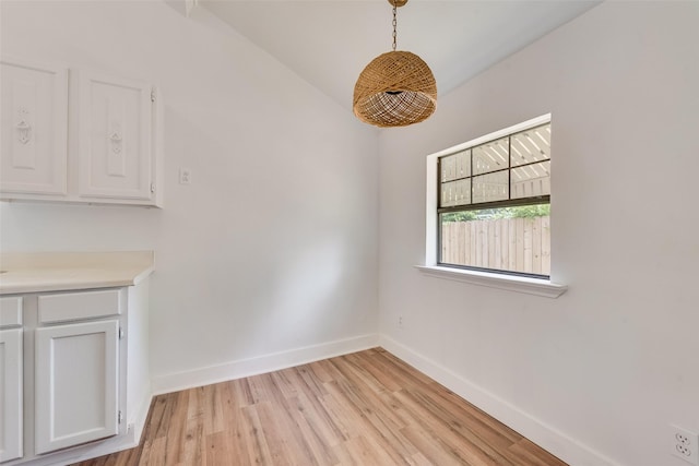 unfurnished dining area with baseboards and light wood-type flooring
