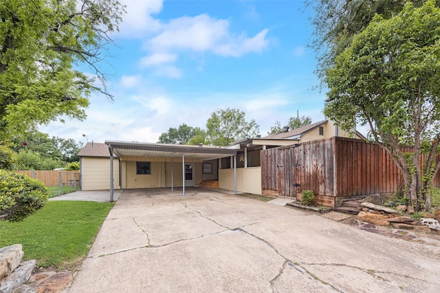 view of front of property featuring concrete driveway, fence, a front lawn, and an attached carport