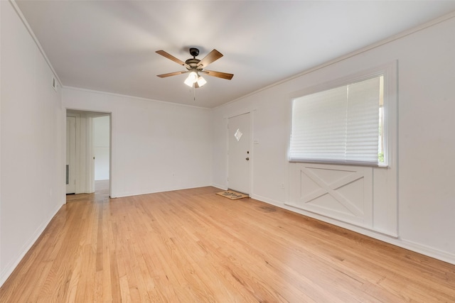 spare room featuring light wood-style floors, baseboards, ceiling fan, and crown molding