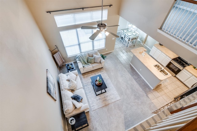 tiled living area featuring a ceiling fan and a high ceiling