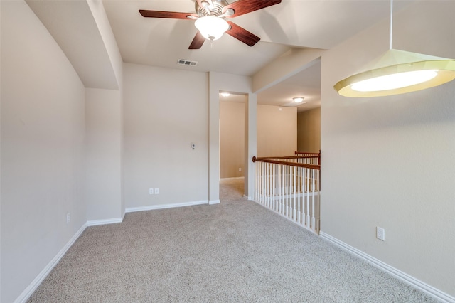 carpeted empty room featuring baseboards, ceiling fan, and visible vents