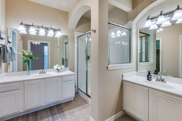 bathroom featuring a sink, a shower stall, and two vanities