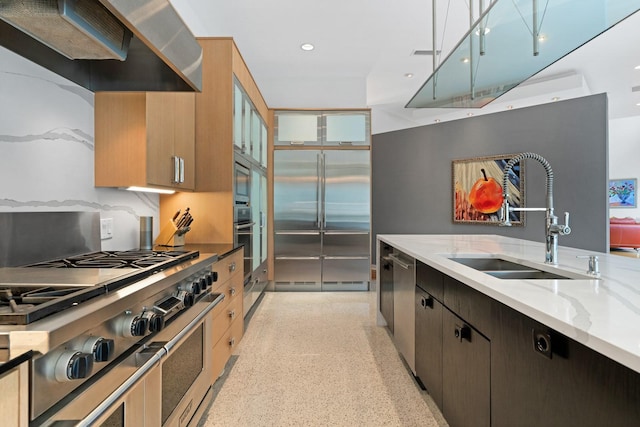 11715 Parwen Dr, Dallas, TX 75230 - kitchen featuring built in appliances, light speckled floor, light stone countertops, wall chimney range hood, and a sink