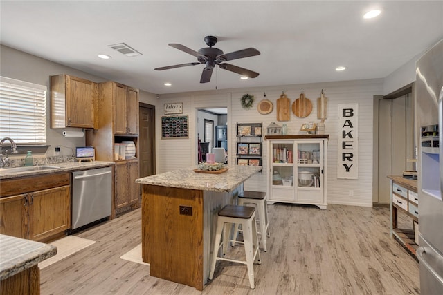 kitchen with visible vents, a ceiling fan, a kitchen bar, a sink, and dishwasher