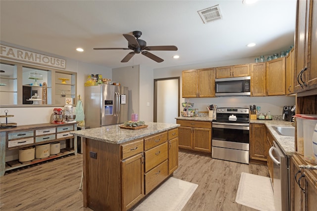 kitchen with ceiling fan, visible vents, appliances with stainless steel finishes, a center island, and light wood-style floors
