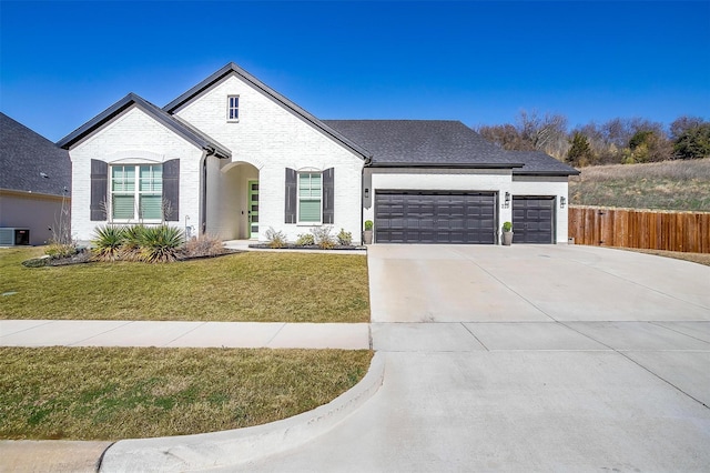 view of front facade with fence, a front lawn, brick siding, a garage, and concrete driveway