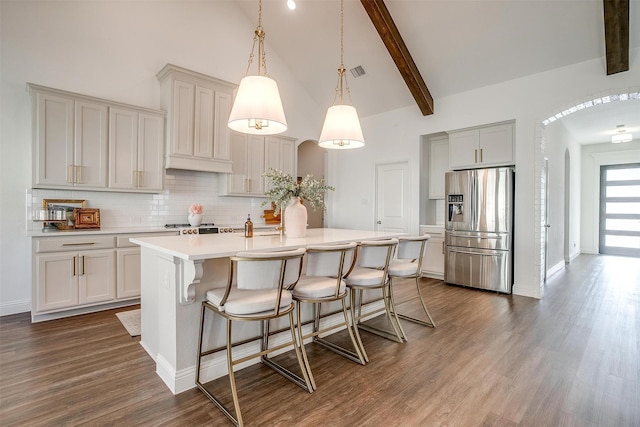 kitchen with decorative backsplash, visible vents, arched walkways, high vaulted ceiling, and stainless steel fridge