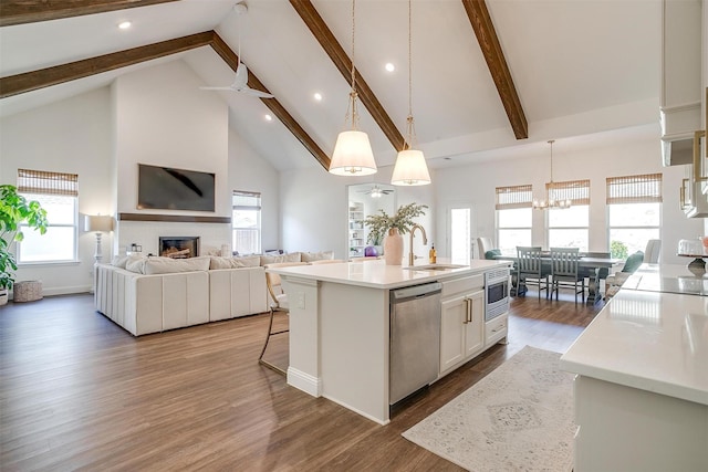 kitchen with a sink, beam ceiling, high vaulted ceiling, a glass covered fireplace, and stainless steel appliances