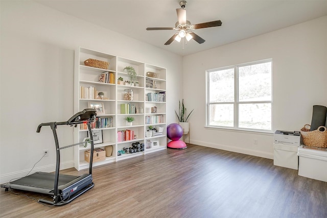 workout area featuring baseboards, a ceiling fan, and wood finished floors