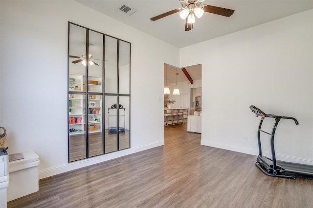 interior space featuring visible vents, a ceiling fan, baseboards, and wood finished floors