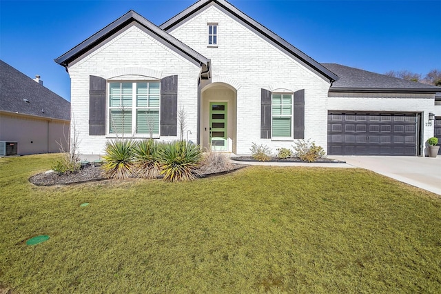 french provincial home with concrete driveway, brick siding, a front lawn, and a garage