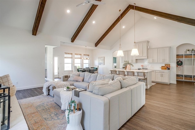 living room featuring wood finished floors, recessed lighting, beam ceiling, and high vaulted ceiling