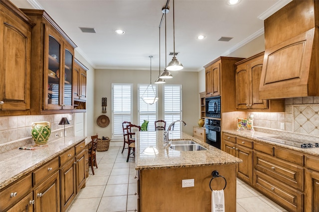 kitchen with a center island with sink, brown cabinets, a sink, light tile patterned floors, and black appliances
