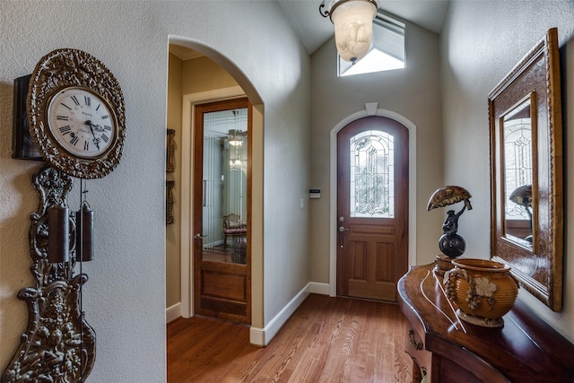 entrance foyer with arched walkways, baseboards, plenty of natural light, and light wood-type flooring