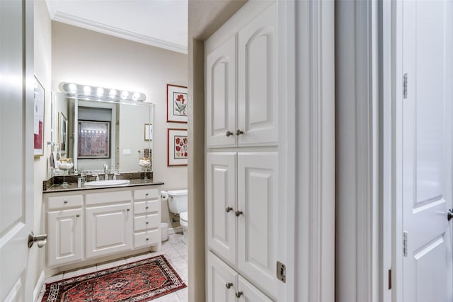 half bathroom with toilet, ornamental molding, tile patterned flooring, and vanity