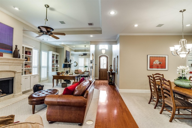 living area with ornamental molding, a fireplace, and ceiling fan with notable chandelier