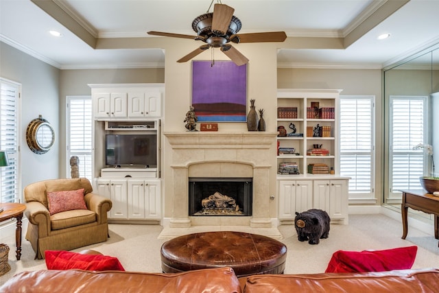 living room featuring ornamental molding, ceiling fan, light carpet, and a fireplace