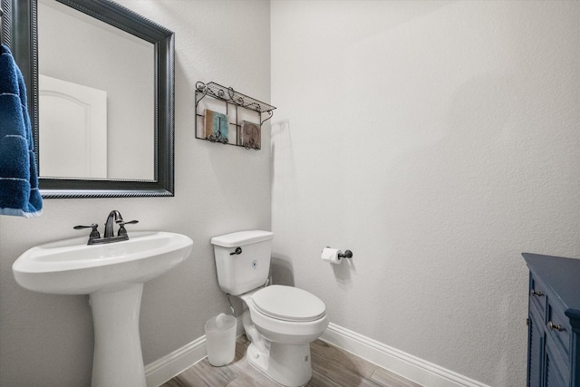 2114 Burke Dr, Princeton, TX 75407 - half bath featuring toilet, baseboards, a sink, and wood finished floors