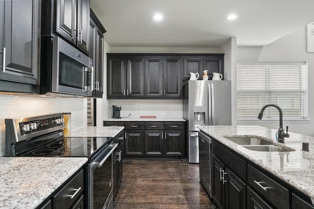 2114 Burke Dr, Princeton, TX 75407 - kitchen featuring appliances with stainless steel finishes, light stone counters, a sink, dark cabinets, and tasteful backsplash
