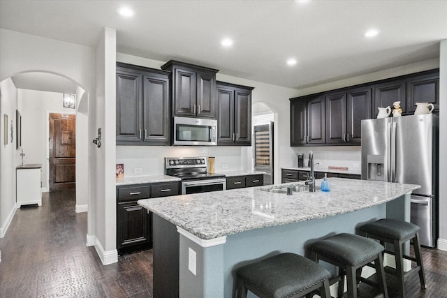 2114 Burke Dr, Princeton, TX 75407 - kitchen featuring dark wood-style flooring, a sink, a breakfast bar, arched walkways, and appliances with stainless steel finishes