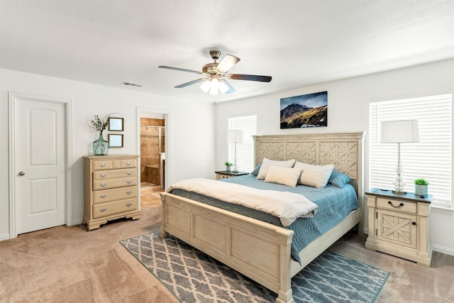bedroom featuring light carpet, a ceiling fan, baseboards, ensuite bathroom, and visible vents