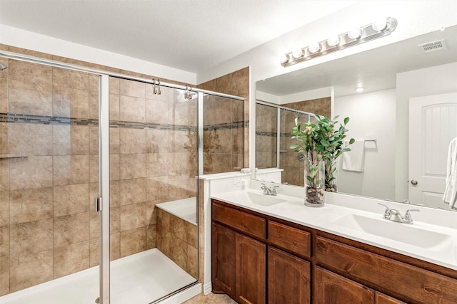 bathroom featuring a sink, a stall shower, double vanity, and visible vents
