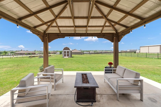 view of patio / terrace featuring a storage shed, a gazebo, fence, and an outdoor living space with a fire pit
