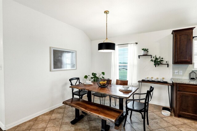 dining space featuring light tile patterned floors, baseboards, and lofted ceiling