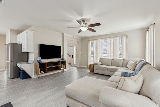 living area featuring baseboards, a ceiling fan, light wood-style floors, and visible vents