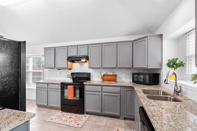 7129 Dee Cole Dr, The Colony, TX 75056 - kitchen with black appliances, gray cabinetry, backsplash, and vaulted ceiling