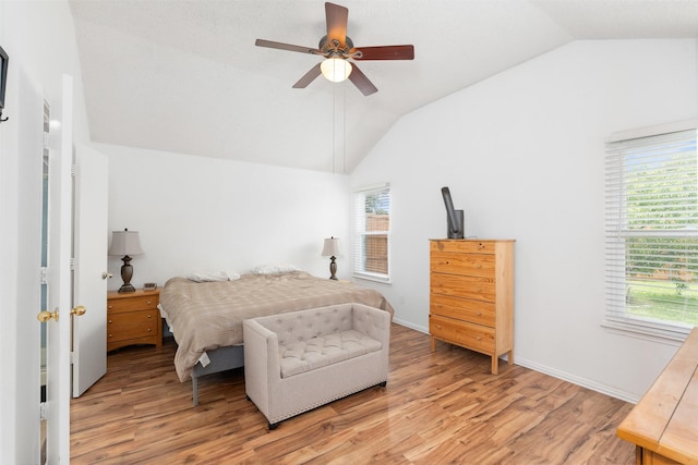bedroom with light wood-style floors, baseboards, a ceiling fan, and lofted ceiling