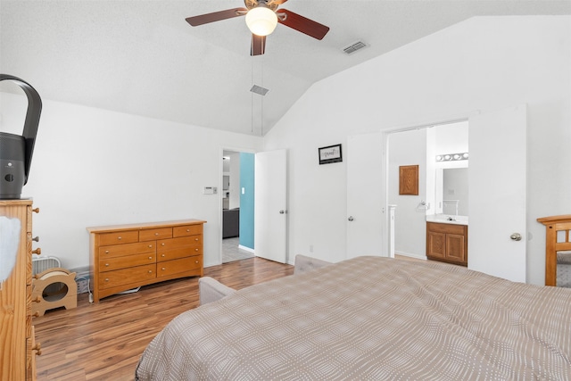 bedroom with visible vents, ensuite bathroom, light wood-type flooring, a ceiling fan, and vaulted ceiling