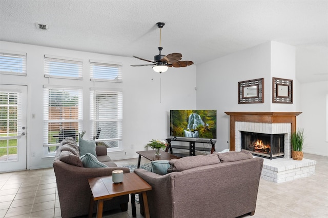7129 Dee Cole Dr, The Colony, TX 75056 - living room with a brick fireplace, light tile patterned floors, a textured ceiling, and ceiling fan