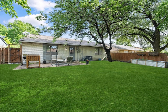 back of house featuring a yard, brick siding, a patio, and a fenced backyard