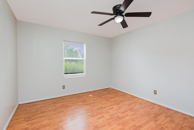 spare room featuring light wood-style floors, baseboards, and ceiling fan