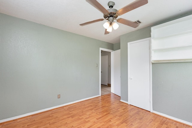 unfurnished bedroom with light wood-type flooring, a ceiling fan, baseboards, and visible vents