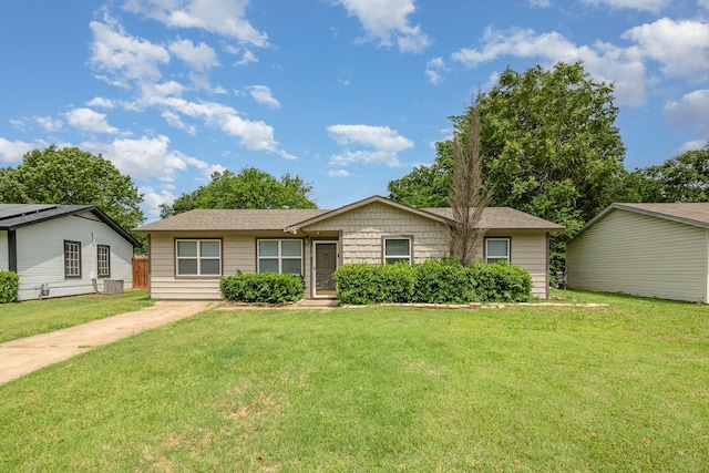 ranch-style house featuring a shingled roof and a front lawn