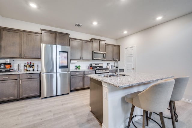1529 Babb Ln, Celina, TX 75009 - kitchen featuring a sink, a kitchen breakfast bar, light wood-style flooring, stainless steel appliances, and visible vents
