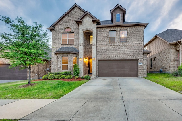 french provincial home featuring an attached garage, a front yard, driveway, and brick siding
