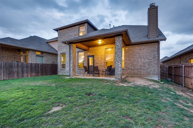 rear view of house with brick siding, a fenced backyard, and a patio area