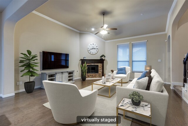 living area featuring crown molding, ceiling fan, a brick fireplace, baseboards, and wood finished floors