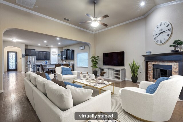 living room with plenty of natural light, ceiling fan, visible vents, arched walkways, and dark wood finished floors