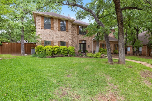 view of front of house featuring brick siding, fence, central air condition unit, and a front yard