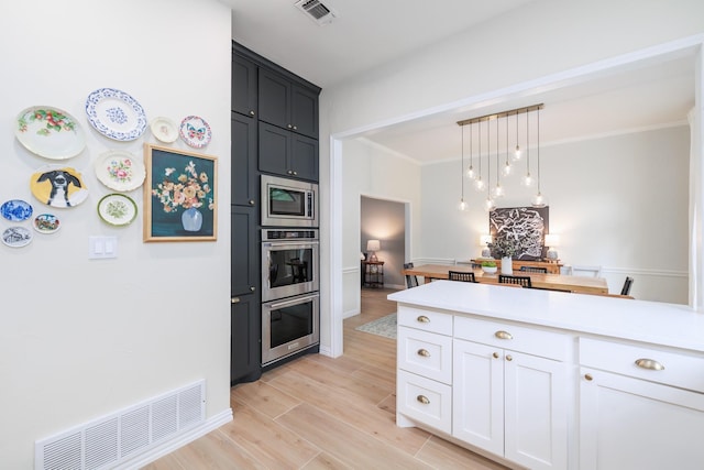 kitchen with light countertops, appliances with stainless steel finishes, light wood-type flooring, and visible vents